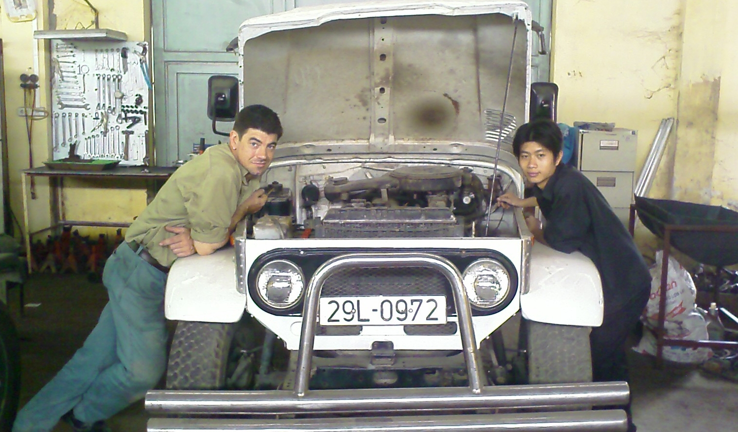 A man working with a young boy and teaching him about working on cars.