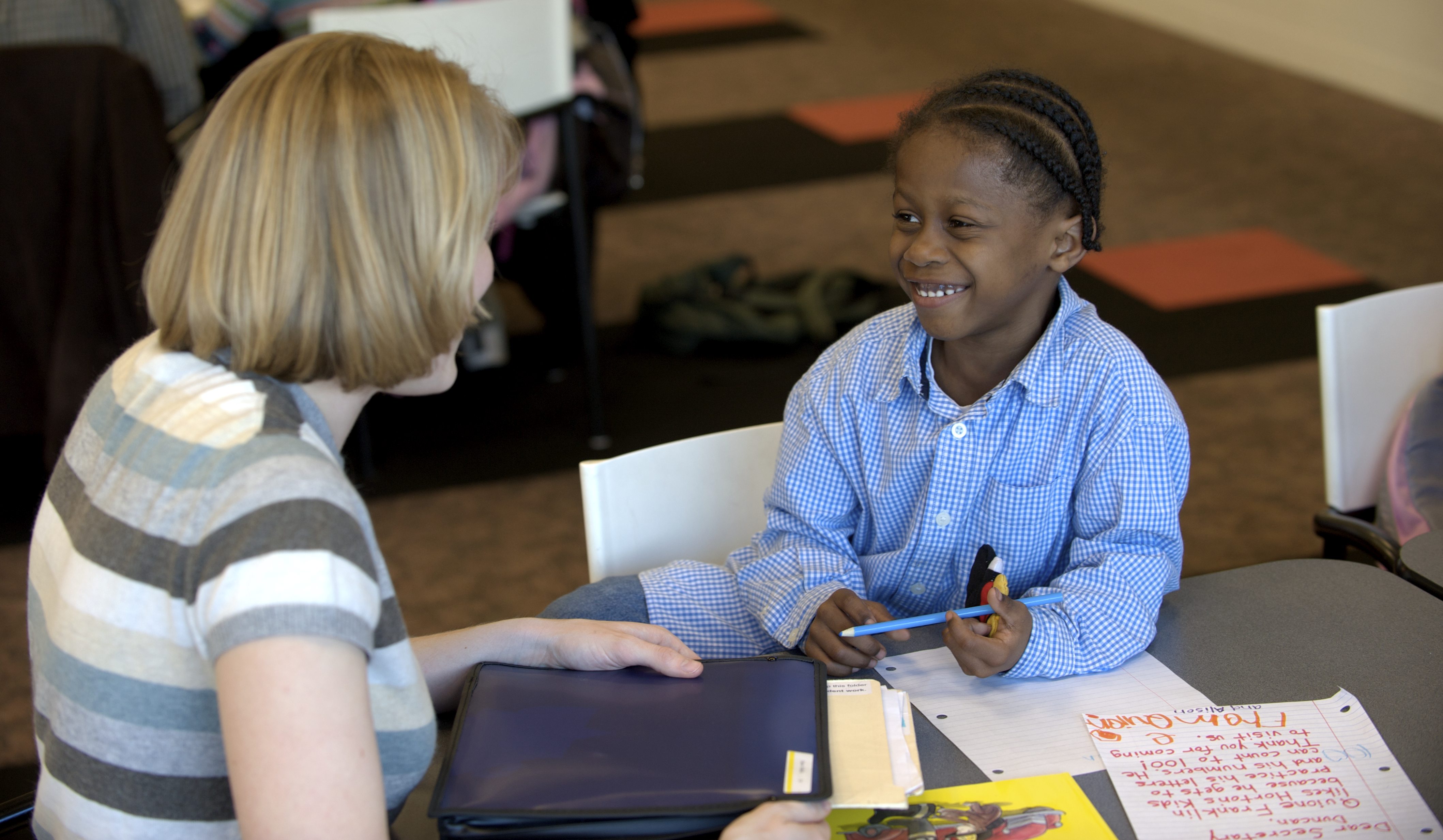 A woman working with a young boy on some homework.